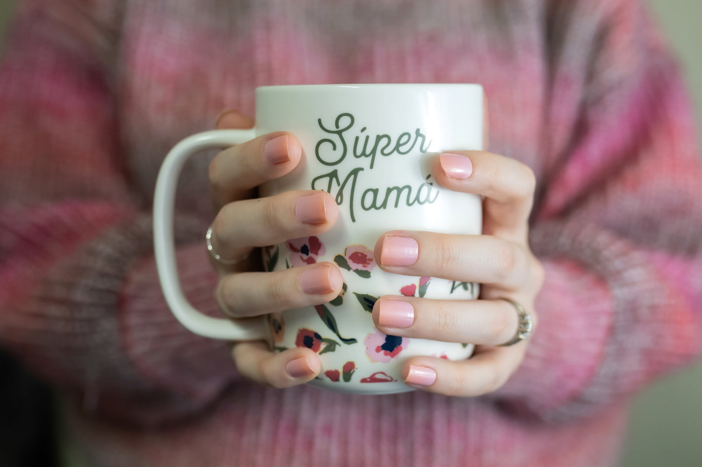 a woman holding a white coffee mug with the words super mama on it