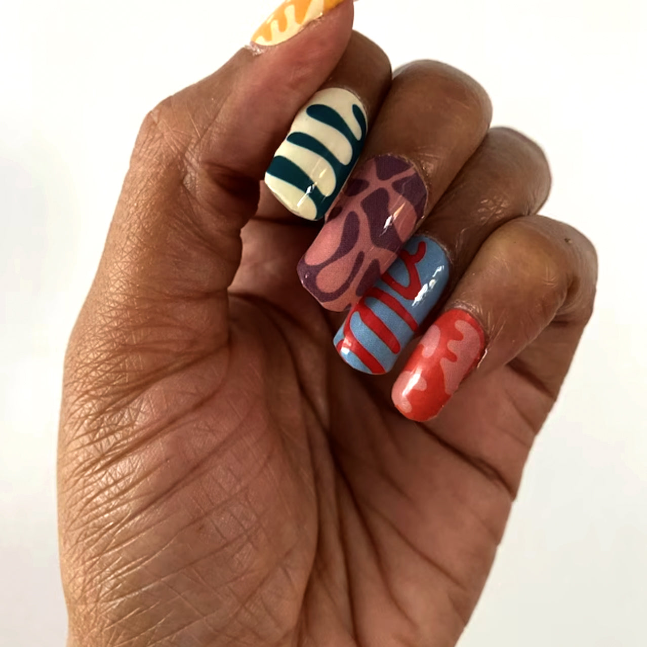 a hand holding a multicolored manicure with different designs